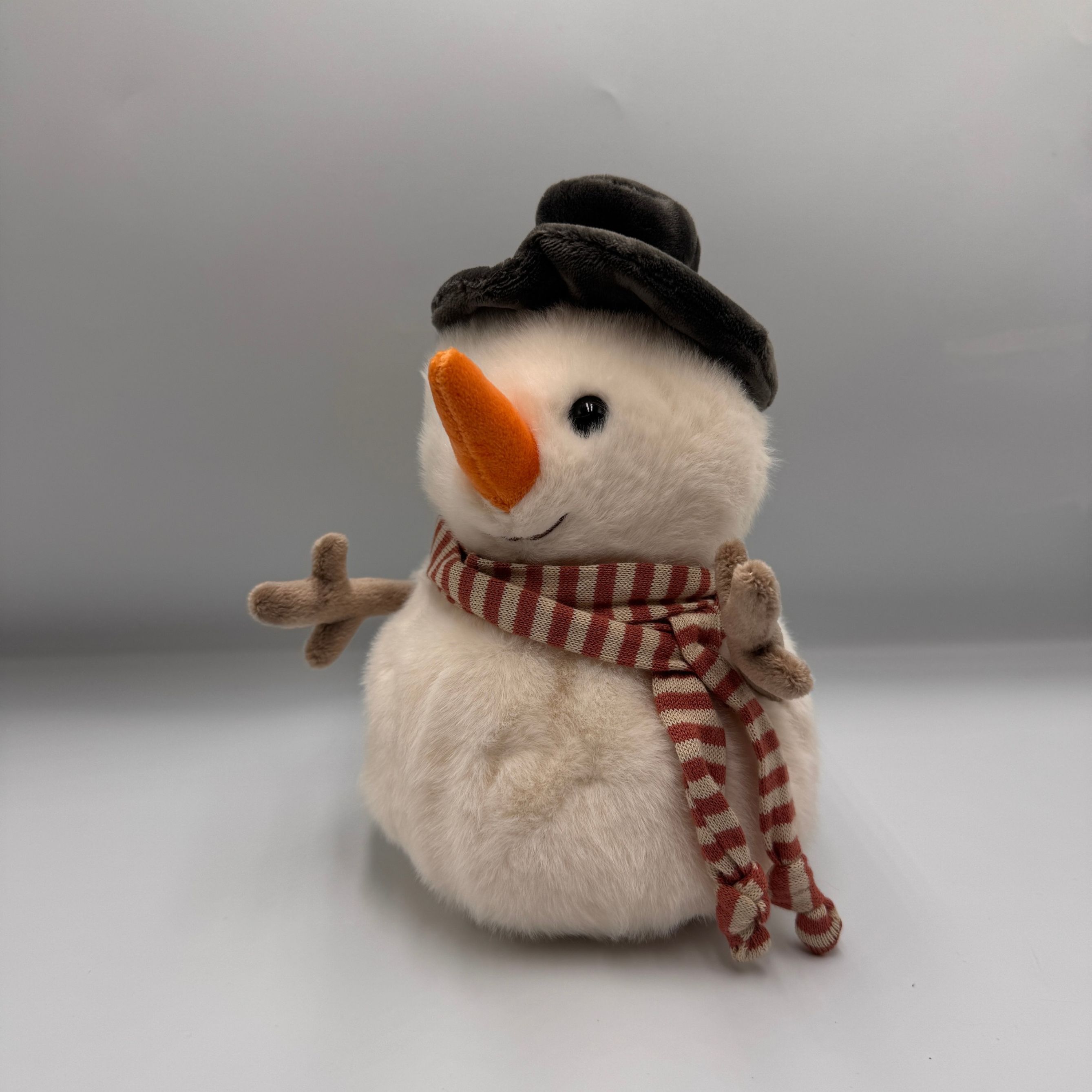 Miś Bukowski Jack the Snowman 25 cm – biały bałwanek z czarnym kapeluszem, pasiastym szalikiem i pomarańczowym nosem.